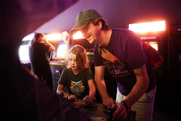 Peter Wischusen and his daughter, Lulu, 7, enjoy playing a game together at Infinite Horizons Arcade. (Abbey Cutrer/AJC)