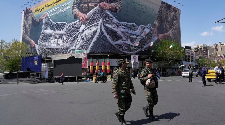 FILE - Two police officers walk in front of an anti-U.S. billboard depicting American aircraft being caught by Iranian armed forces in a fishing net beneath the words in Farsi, "The Strait of Hormuz will remain closed, The entire Persian Gulf is our hunting ground," in Tehran, Iran, Sunday, April 5, 2026. (AP Photo/Vahid Salemi, File)