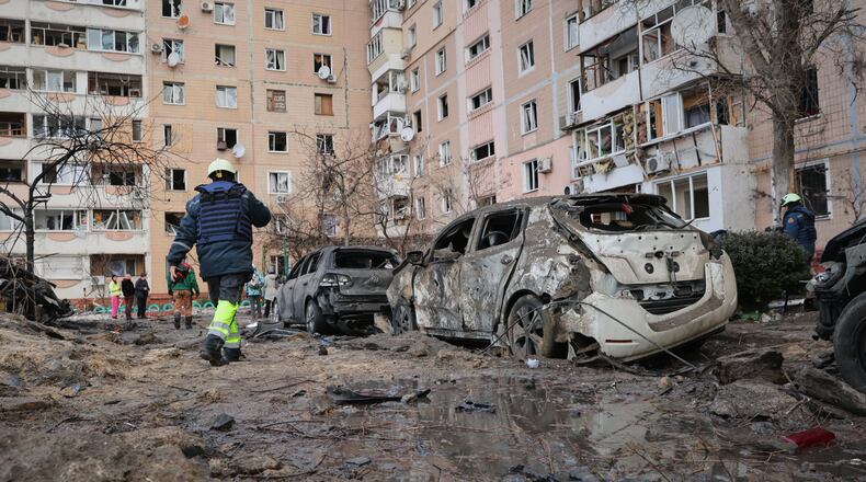 People pass by damaged cars near an apartment building after a Russian attack in Zaporizhzhia, Ukraine, Wednesday, Jan. 28, 2026. (AP Photo/Kateryna Klochko)