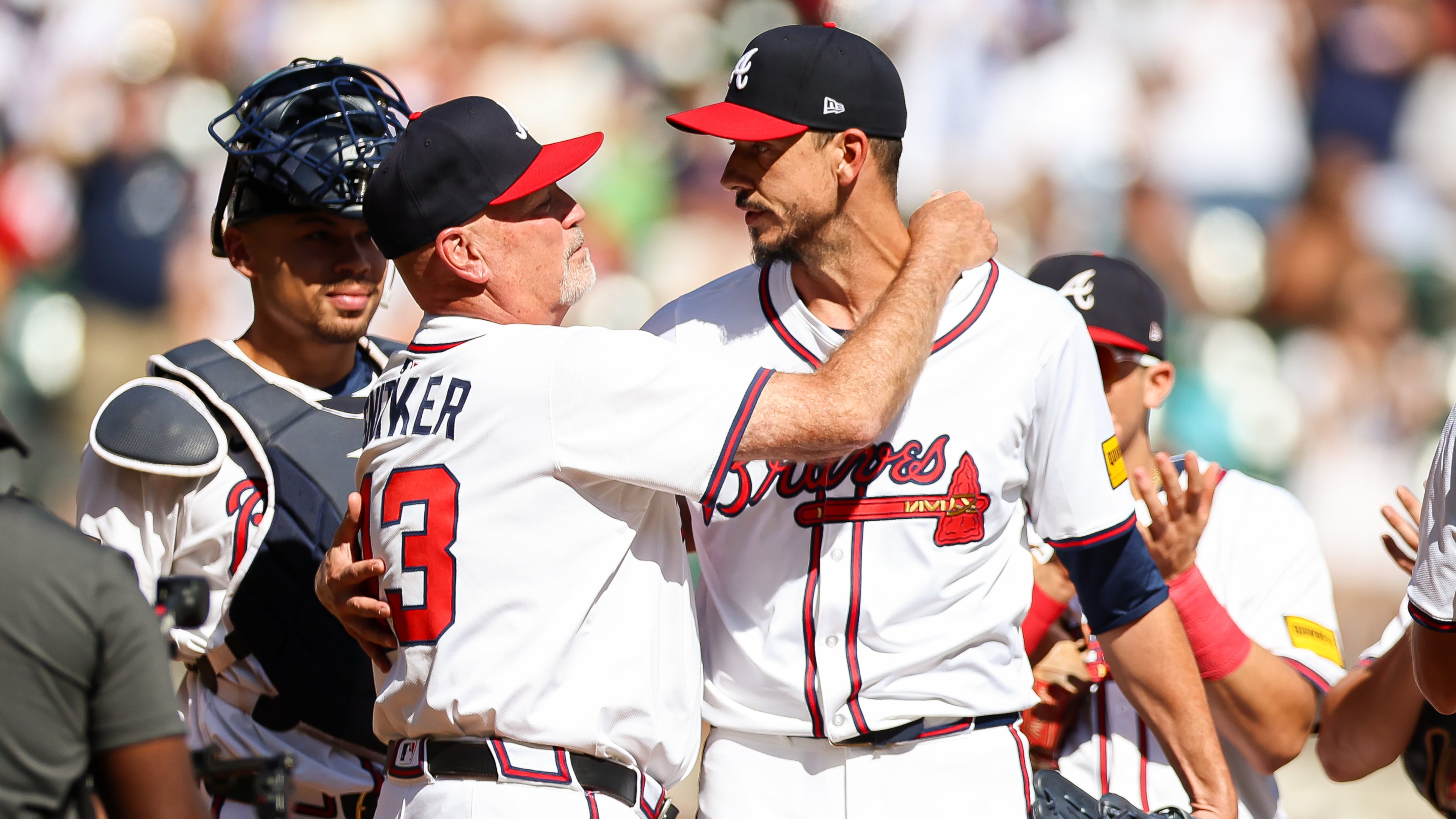 Atlanta Braves manager Brian Snitker, front left, hugs pitcher Charlie Morton, front right, during the second inning of a baseball game against the Pittsburgh Pirates, Sunday, Sept. 28, 2025, in Atlanta. (AP Photo/Colin Hubbard)
