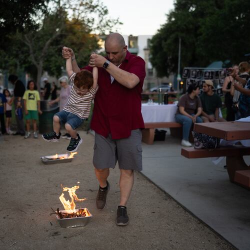 Sohrab Yassan lifts his son over a small fire as they participate in Chaharshanbe Suri, a traditional festival leading up to the Nowruz holiday, during a community gathering in the Encino neighborhood of Los Angeles, March 17, 2026. (AP Photo/Jae C. Hong)