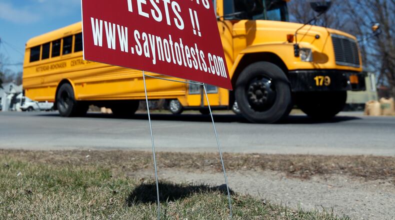 A school bus passes a sign encouraging parents to refuse that their children take state tests in Rotterdam, N.Y. (AP Photo/Mike Groll)