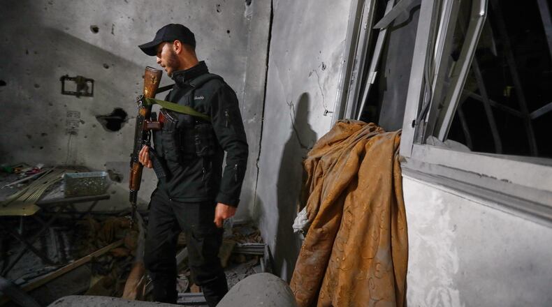 A Syrian Internal Security Forces officer inspects a home in Damascus, Syria, Friday, Nov. 14, 2025, after it was hit by rockets, according to state media. It was not immediately clear who was behind the attack. (AP Photo/Omar Sanadiki)