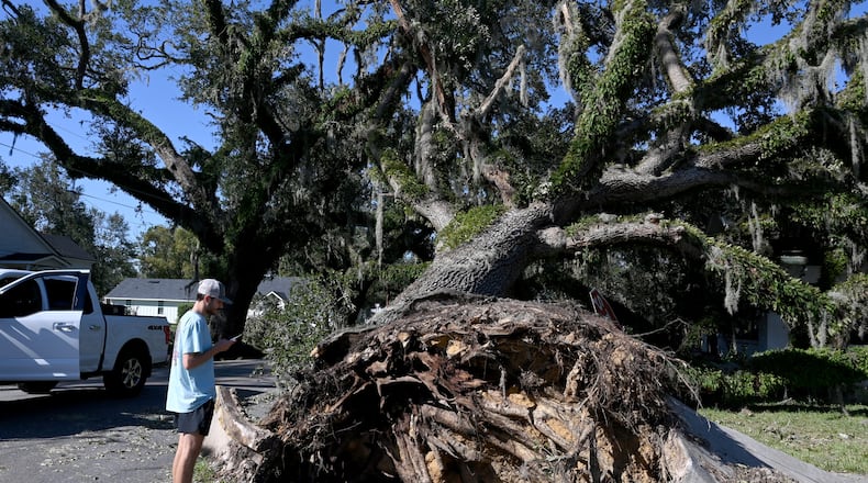 Nealy Hiers, student at Valdosta State University, takes a picture of a fallen tree caused by Hurricane Helene near Valdosta State University, Saturday, September 28, 2024, in Valdosta. The devastation in Valdosta was extensive after the South Georgia city was battered with hurricane-force winds on Helene’s path across the state. Damaging Helene has swept through Georgia, leading to at least 15 deaths. All 159 counties are now assessing the devastation and working to rebuild, even as serious flooding risks linger. (Hyosub Shin / AJC)