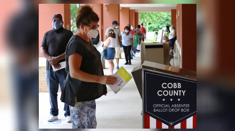 Nina Wilson drops off her absentee ballot while dozens of other voters line up to cast their votes in person on the first day of early voting at the Cobb County Board of Elections & Registration on Monday, May 18, 2020, in Marietta.   Curtis Compton ccompton@ajc.com