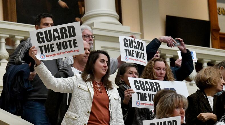 Paper ballot supporters hold signs during a press conference outside State Election Board meeting at the Georgia State Capitol building, Tuesday, December 19, 2023, in Atlanta. (Hyosub Shin/Hyosub.Shin@ajc.com)