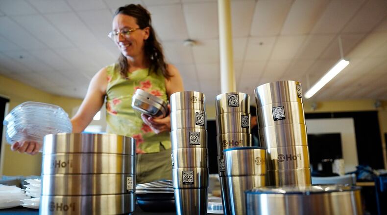 Bethany Letoto, business development lead at Ho'i, a returnable dish program, sets out the re-useable containers before an open house on Tuesday, June 30, 2026, in Hilo, Hawaii. (Kevin Fujii/Honolulu Civil Beat via AP)