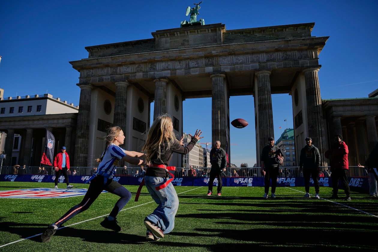 Children play flag football on a mini flag football field, set up in front of the Brandenburg Gate in Berlin, Germany, Thursday, Nov. 6, 2025, during an event promoting the NFL ahead of the upcoming game between the Indianapolis Colts and the Atlanta Falcons. (AP Photo/Ebrahim Noroozi)
