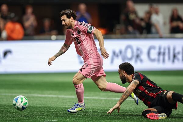 Inter Miami forward Lionel Messi, left, dribbles past Atlanta United defender Derrick Williams, right, before scoring in the first half of an MLS soccer match Sunday, March, 16, 2025, in Atlanta. (AP Photo/Colin Hubbard)