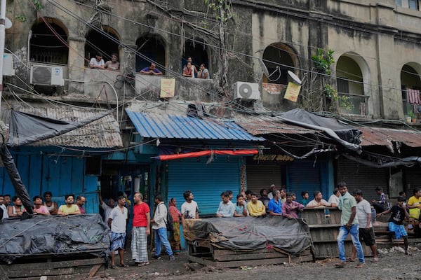Local people gather in front of a hotel building which caught fire on Tuesday resulting in several deaths, in Kolkata, India, Wednesday, April 30, 2025. (AP Photo/Bikas Das)