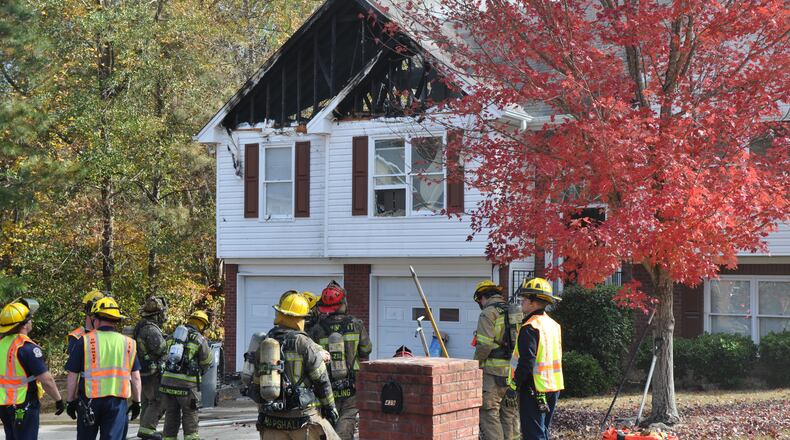Firefighters work to extinguish a fire that originated in the attic of a two-story house in Gwinnett County.