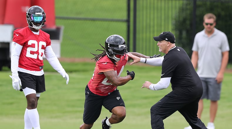 Atlanta Falcons head coach Dan Quinn blocks Devonta Freeman while working with the running backs with Tevin Coleman looking on during organized team activity on Wednesday, May 30, 2018, in Flowery Branch.  Curtis Compton/ccompton@ajc.com