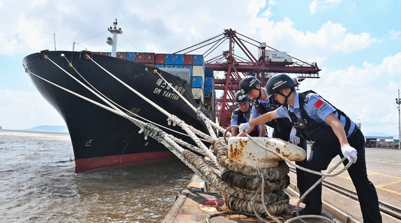 In this photo released by Xinhua News Agency, police officers check the mooring lines of a vessel ahead of Typhoon Dolphin in Beilun District of Ningbo City, east China's Zhejiang Province, on Aug. 7, 2026.(Hu Jiajie/Xinhua via AP)