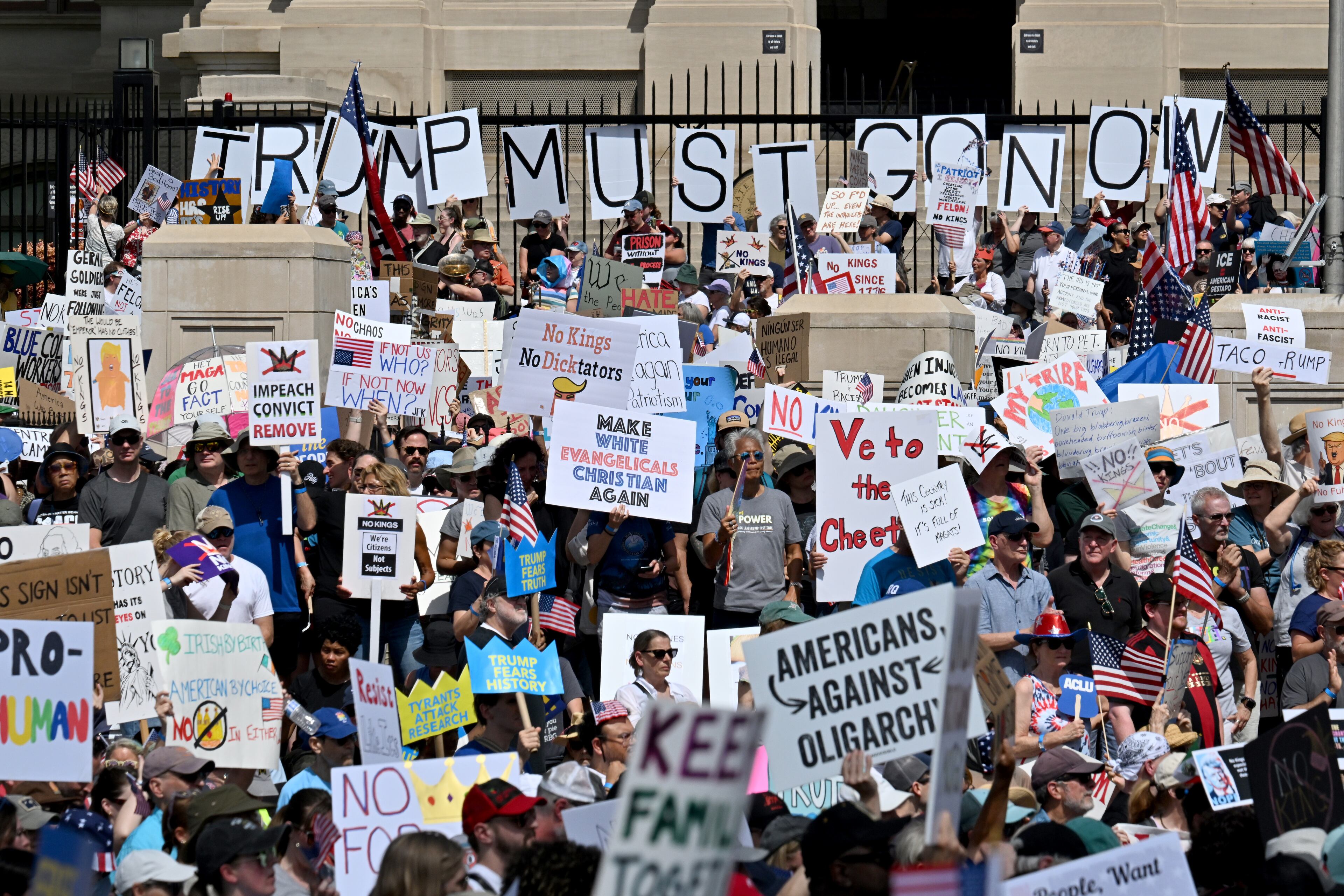 Demonstrators hold signs outside the Georgia Capitol during a "No Kings" protest to oppose Trump’s immigration policies, Saturday, June 14, 2025, in Atlanta. (Hyosub Shin / AJC)