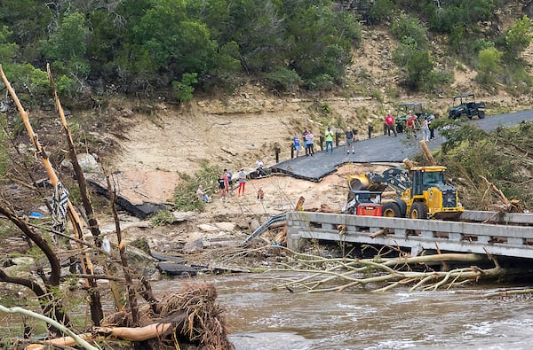 Crews work to clear debris from the Cade Loop bridge along the Guadalupe River on Saturday, July 5, 2025, in Ingram, Texas. (AP Photo/Rodolfo Gonzalez)