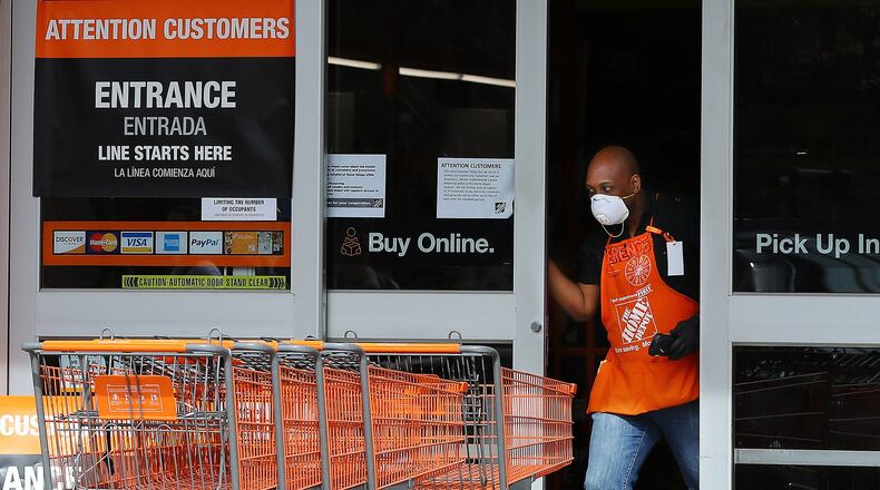 A Home Depot employee opens the doors to the store at Midtown Place to let the next few customers in while the store limits the number of occupants to maintain six feet of space between shoppers and help prevent the spread of coronavirus on March 29, 2020, in Atlanta. Curtis Compton ccompton@ajc.com