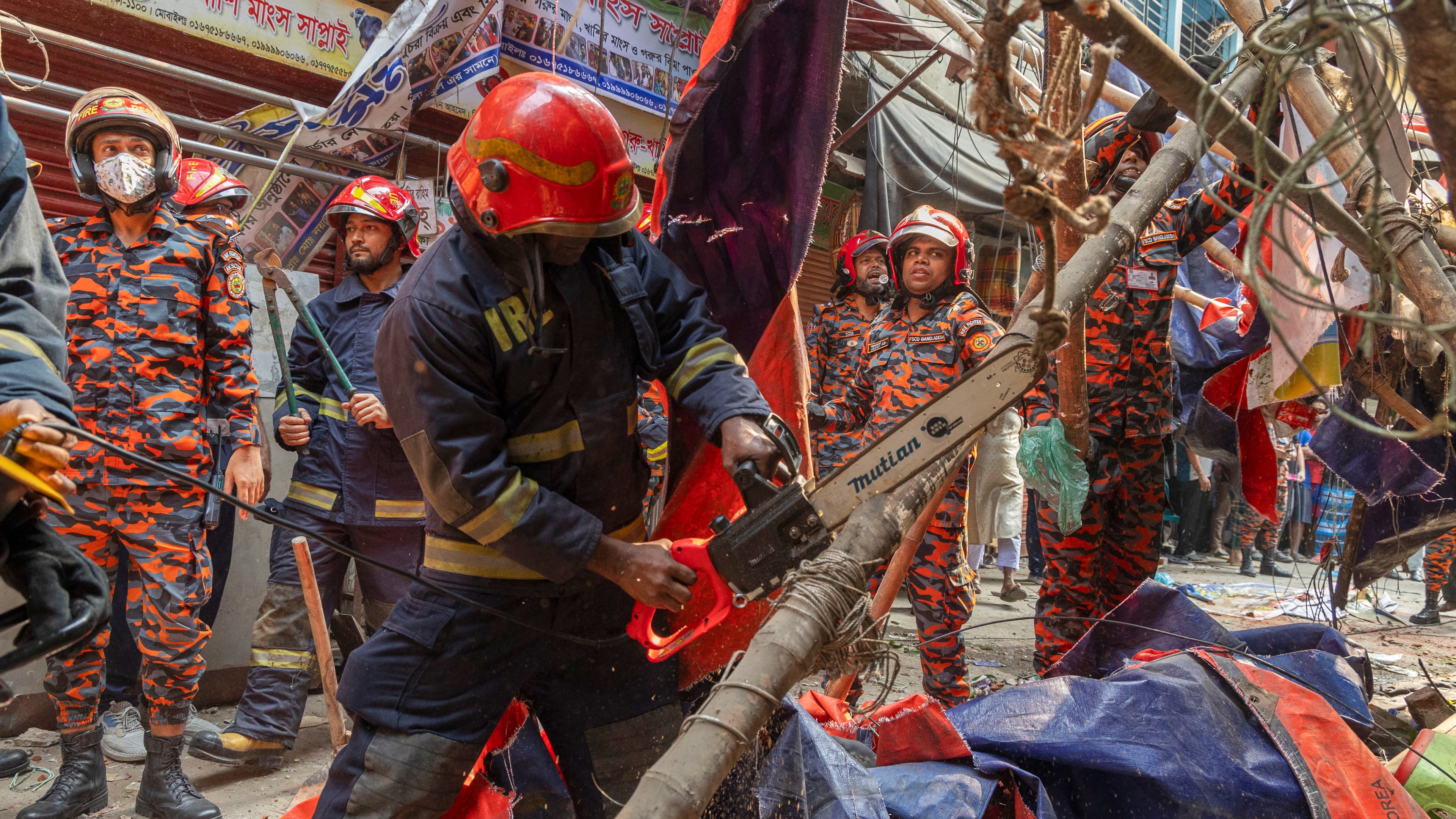Rescue and fire officials cut building railings falling on the street to make way after an earthquake in Dhaka, Bangladesh, Friday, Nov. 21, 2025. (AP Photo/Abdul Goni)