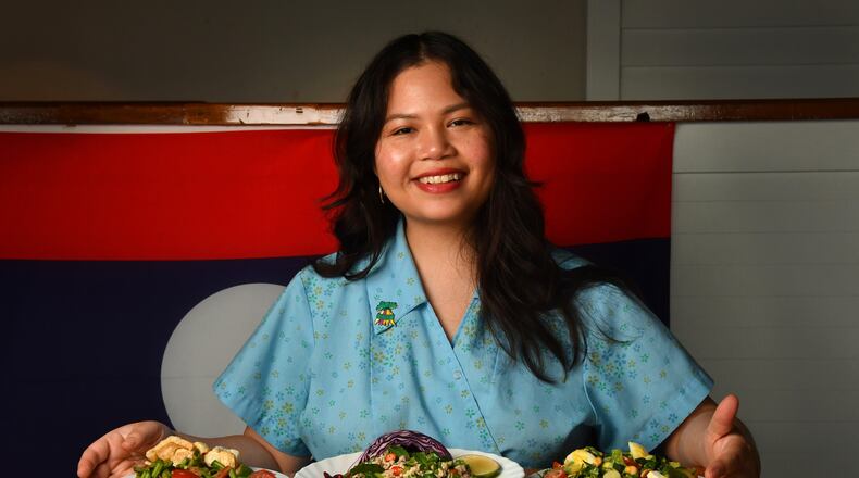 Lao American Ilene Rouamvongsor, an Atlanta-based recipe developer, food stylist and food educator, poses with three of her Lao salads: (from left) Thum Mak Tua (Long Bean Salad), Laab Gai (Chicken Salad) and Yum Salat (Lao Salad with Egg Dressing). (Styling by Ilene Rouamvongsor / Chris Hunt for the AJC)