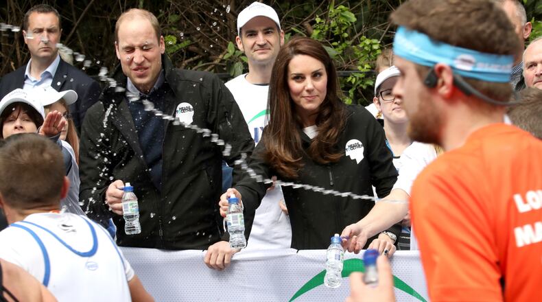 A runner squirts water towards Britain's Prince William, the Duke of Cambridge, as he hands out water to runners during the London Marathon in London, Sunday.
