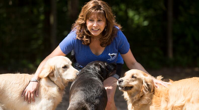 Susie Aga, founder of Atlanta Dog Trainer, a "premier dog training and behavior modification center in the Southeast," with dogs at her facility.