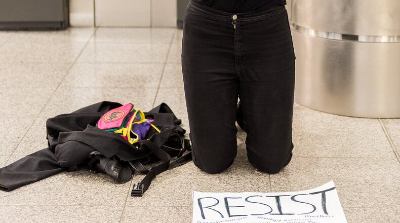 A protester prays on the floor of the domestic South Terminal at Hartsfield-Jackson International Airport as other protesters march inside on Sunday, Jan. 29, 2017. CORY HANCOCK /FOR THE AJC