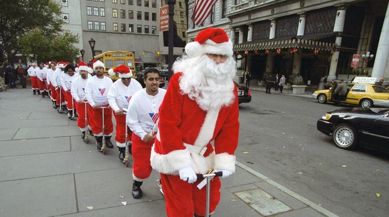 UNITED STATES - CIRCA 2000: Chief Santa Claus Cliff Schneider leads a troop of potential Volunteers of America sidewalk Santas as they scoot through a training session at the Plaza hotel. They were told not to eat garlic or raw onions on duty and to keep "Ho-ho-hos" jovial and joyous, among other things learned in "Santa-class." (Photo by Budd Williams/NY Daily News Archive via Getty Images)