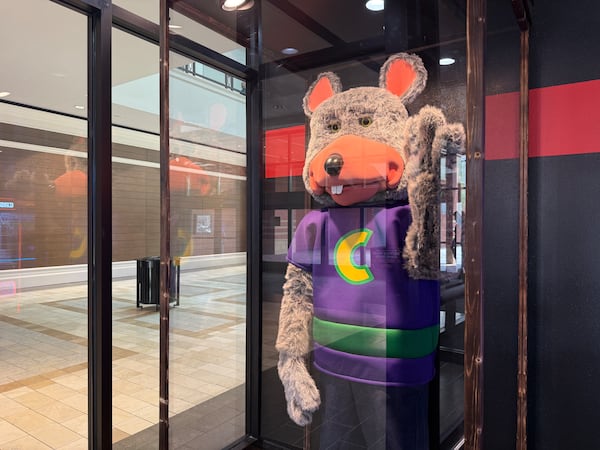 An animatronic version of franchise mascot Chuck, part of the Munch's Make Believe Band that Chuck E. Cheese phased out in the 2020s, is enshrined in a glass display case at the entrance to the Buford location of Chuck's Arcade. (Danielle Charbonneau/AJC)