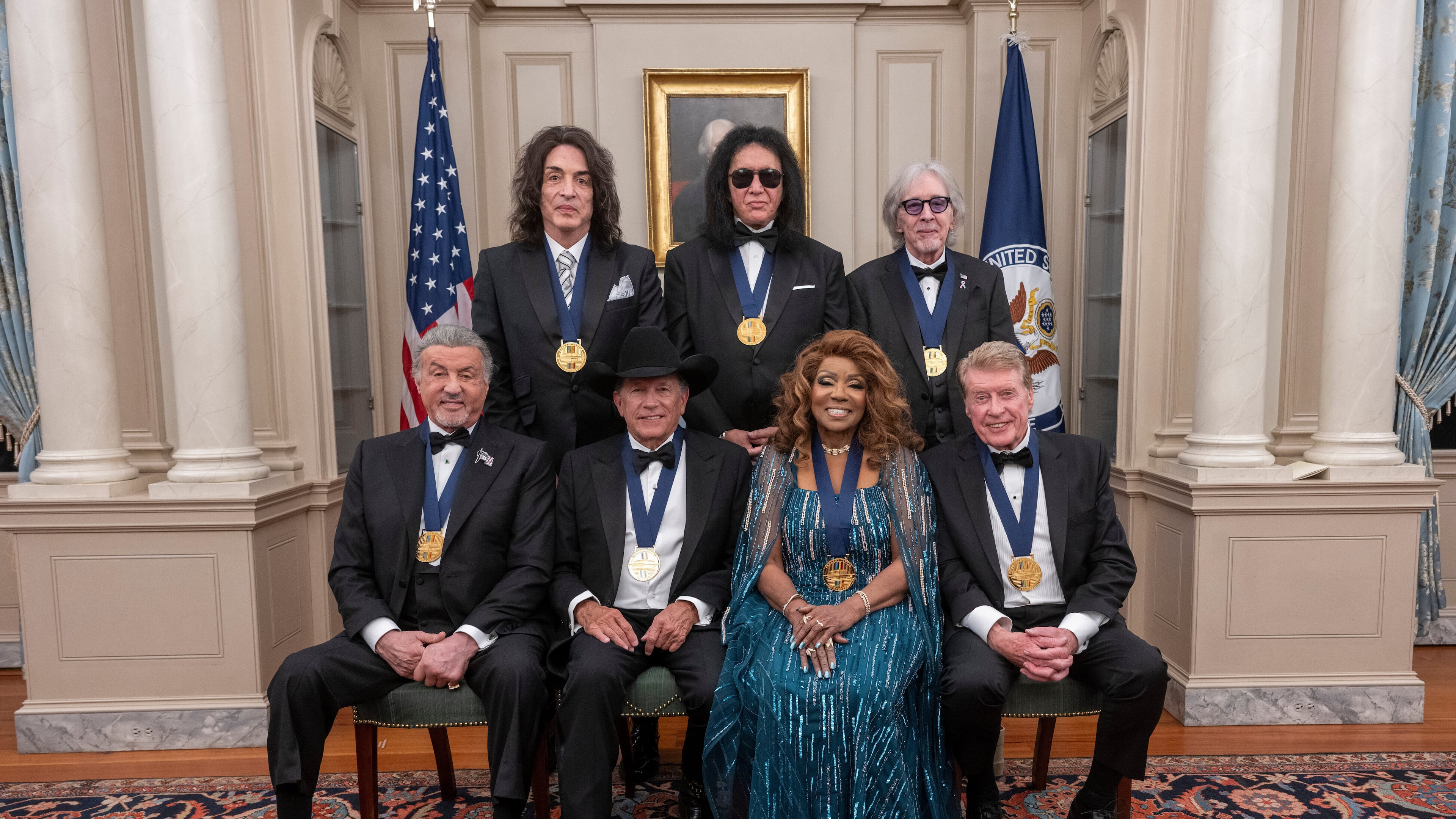 The 2025 Kennedy Center Honorees, front row from left, Sylvester Stallone, George Strait, Gloria Gaynor and Michael Crawford; back row from left, members of the rock band KISS, Paul Stanley, Gene Simmons and Peter Criss, pose for a group photo at the 48th Kennedy Center Honors Medallion Reception, hosted at the U.S. Department of State, Saturday, Dec. 6, 2025 in Washington. (AP Photo/Kevin Wolf)