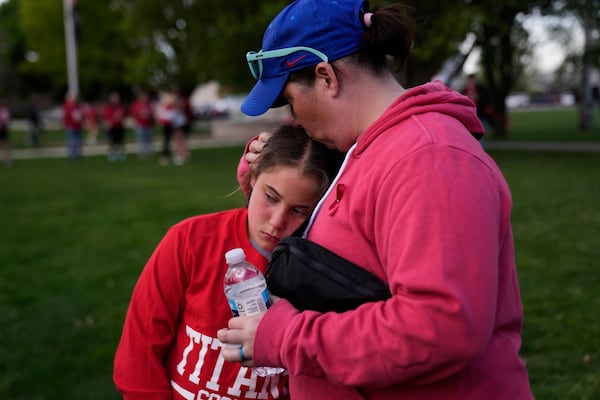 Heather Glessner comforts her 9-year-old daugher Coralie at a vigil for three young children and a teenager who were killed when a car barreled through a building used for an after-school camp, Tuesday, April 29, 2025, in Chatham, Ill. (AP Photo/Erin Hooley)