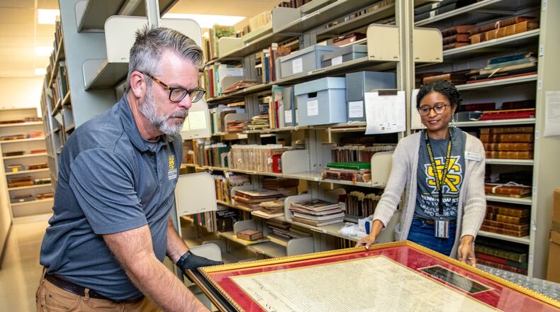 Kennesaw State University’s Tony Howell (left), an exhibit designer, and JoyEllen Williams (right), the curator of the Bentley Rare Book Museum at KSU, prepare to send a rare 1843 copy of the Declaration of Independence to professional conservation on Friday, June 9, 2023.  The historic item is expected to be cleaned and repaired before returning to KSU for display and programming. (Jenni Girtman for The Atlanta Journal-Constitution)