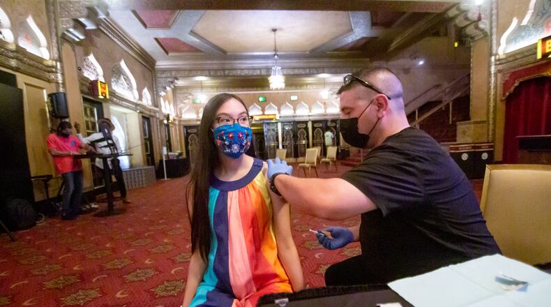 Advanced EMT Michael Williams prepares to give Eva Carrara a COVID vaccine in the lobby of the Fox Theatre on a recent evening. Across the state, an army of medical professionals, public health workers and volunteers for nonprofits are fanning out to reach millions more unvaccinated Georgians, even as the state’s vaccination rate has been dropping. (Steve Schaefer for The Atlanta Journal-Constitution)