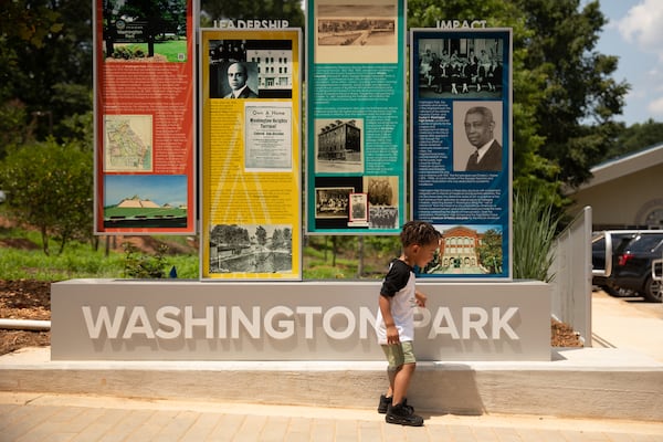 Two-year-old Epic Jones passes in front of the new Washington Park historical sign that highlights the history of Atlanta's earliest, planned Black neighborhoods on Monday, June 23, 2025. (Riley Bunch/AJC)