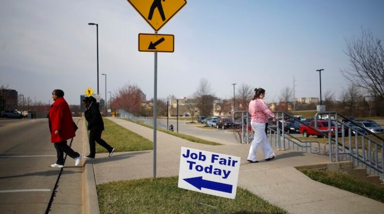Pedestrians pass in front of signage displayed outside a Job News USA career fair in Overland Park, Kansas, U.S., on March 8, 2017. MUSTS CREDIT: Bloomberg photo by Luke Sharrett.