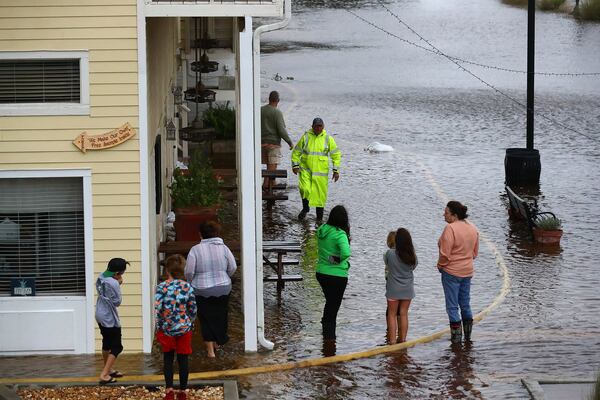 092922: Store owners Angie and Jimmy Mock, friends, family and local residents watch as rising flood waters from Tropical Storm Ian surround their family business Market on the Square during high tide  in historic downtown St. Marys.  Curtis Compton / AJC file photo