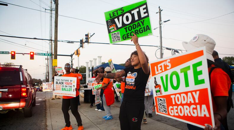 Volunteers encourage citizens to vote on Tuesday, Nov. 8, 2022, across the street from the Metropolitan Library in Atlanta. (Christina Matacotta for The Atlanta Journal-Constitution)