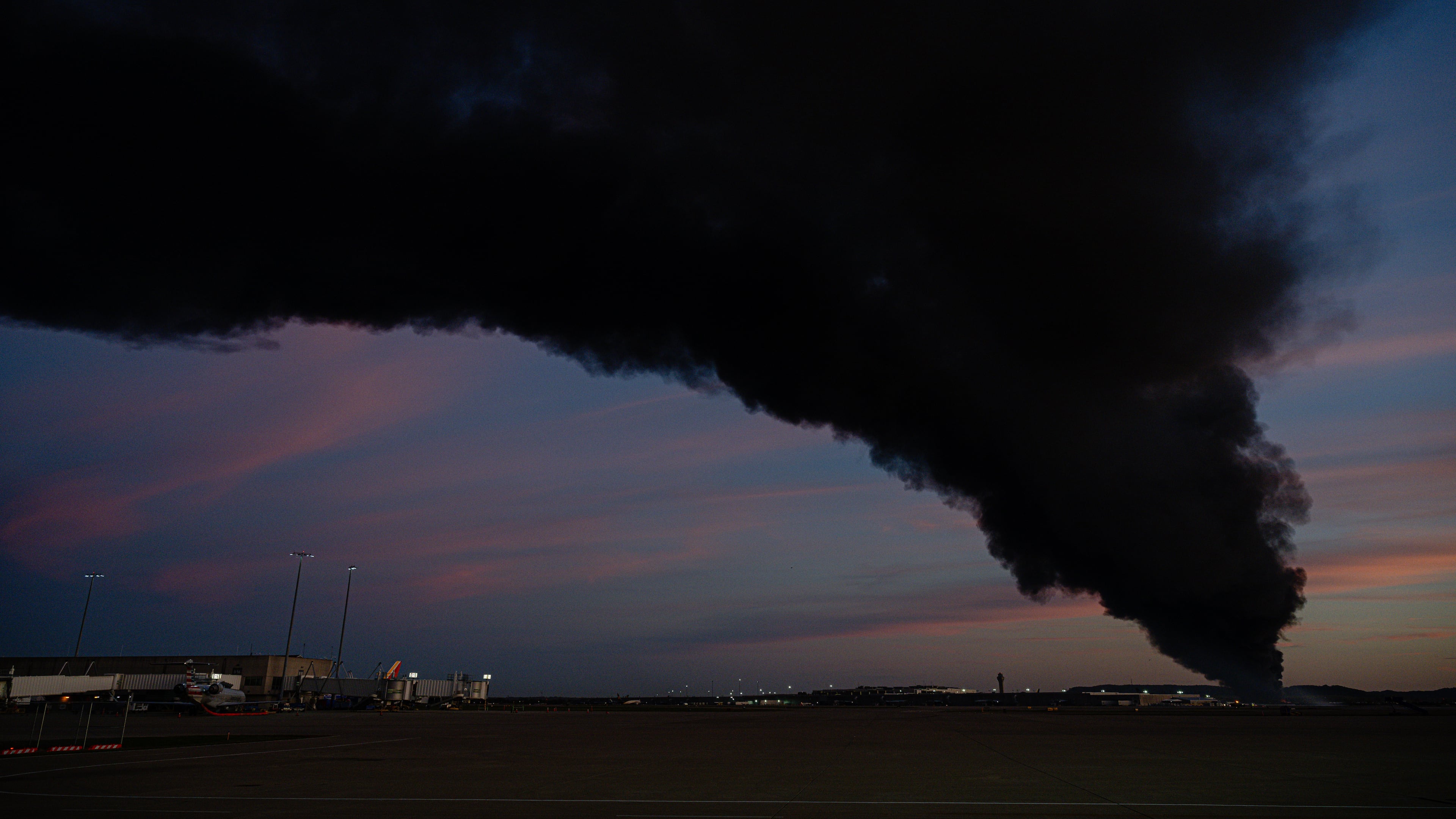 A plume of smoke wafts over airport property after reports of a plane crash at Louisville International Airport, Tuesday, Nov. 4, 2025, in Louisville, Ky. (AP Photo/Jon Cherry)