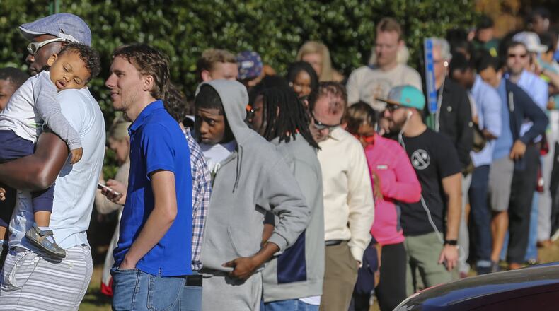 Simon Mbock stood in line for an hour with his son, Oliver, on Friday, Nov. 4, 2016, on the last day of early voting at the Windy Hill Community Center in Smyrna. JOHN SPINK /JSPINK@AJC.COM
