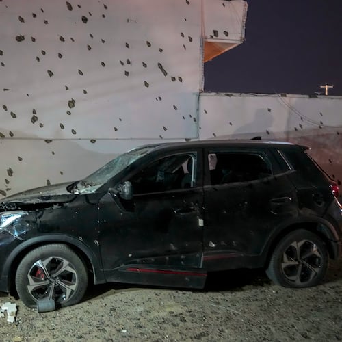 A damaged car sits beside a wall bearing numerous impact marks near the site of a strike in Lamerd, southern Iran, Saturday, Feb. 28, 2026. (Alireza Ameri/Tasnim News Agency via AP)
