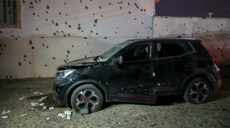 A damaged car sits beside a wall bearing numerous impact marks near the site of a strike in Lamerd, southern Iran, Saturday, Feb. 28, 2026. (Alireza Ameri/Tasnim News Agency via AP)