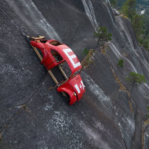 The shell of a Volkswagen Beetle hangs suspended on a cliff above the Sea-to-Sky Highway, in Squamish, British Columbia, Monday, April 6, 2026, after it appeared on the rock face last week with a large "E" on its roof, indicating that University of British Columbia engineering students carried out a long-standing tradition of placing the shell in difficult to reach locations. (Darryl Dyck/The Canadian Press via AP)