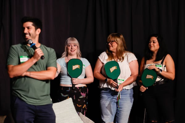 Contestants hold up green paddles for Bijan Golshai during the live dating game show “Game. Set. Match.” held at Limelight Theater in Atlanta. As the taste for apps has soured, the taste for face-to-face dating events has sweetened. (Natrice Miller/AJC)