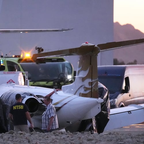 FILE - Investigators look at a crashed Learjet at Scottsdale Airport after it collided with a parked plane Feb. 10, 2025, in Scottsdale, Ariz. (AP Photo/Ross D. Franklin, File)
