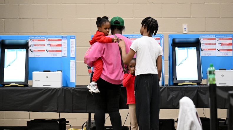 Erica Bryant holds her 2-year-old daughter Atiyah, 2, as she fills out her ballot while her other children are waiting on Election Day at Gracepointe Church of the Nazarene, Tuesday, November 5, 2024, in Loganville.(Hyosub Shin / AJC)