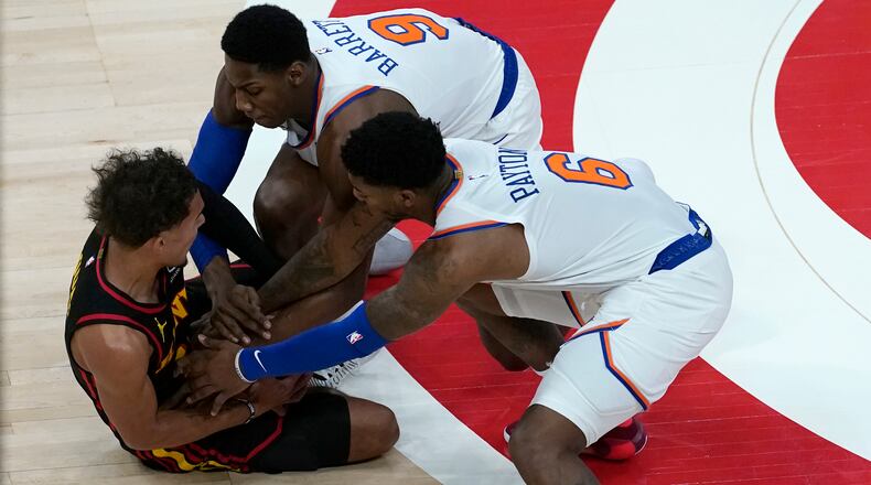 Atlanta Hawks guard Trae Young (11) battles New York Knicks guards Elfrid Payton (6) and RJ Barrett (9) for the ball during the first half of Monday's game in Atlanta.
