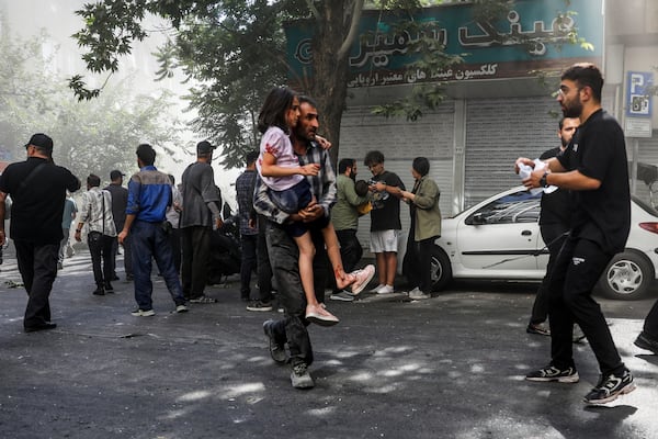 A man carries a wounded girl after an explosion in downtown Tehran amid Israel's two-day campaign of strikes against Iran, Sunday, June 15, 2025. (AP Photo/Morteza Zangene/ISNA)