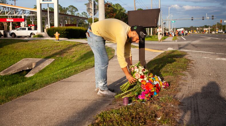 Edgar Olalde, of Jacksonville, who knew the victim from his store, lays a bouquet of flowers during a vigil for a Mexican man who was struck and killed by a tractor trailer while running from an encounter with Immigration and Customs Enforcements officers the day before, Wednesday, July 15, 2026, in St. Augustine, Fla. (AP Photo/Kelly Jordan)
