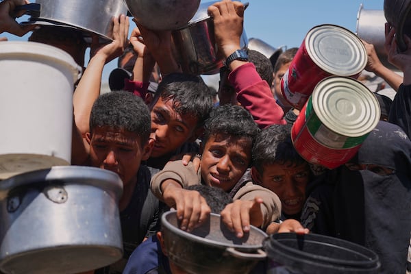 Palestinians struggle to get donated food at a community kitchen in Khan Younis, southern Gaza Strip, Monday, June 2, 2025. (AP Photo/Abdel Kareem Hana)