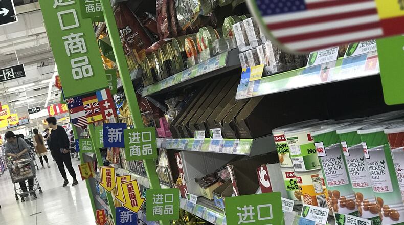 Women push a shopping cart near nuts and sweets imported from the United States and other countries displayed on a section selling imported foods at a supermarket in Beijing, Monday, April 2, 2018. China raised import duties on a $3 billion list of U.S. pork, fruit and other products Monday in an escalating tariff dispute with President Donald Trump that companies worry might depress global commerce. (AP Photo/Andy Wong)