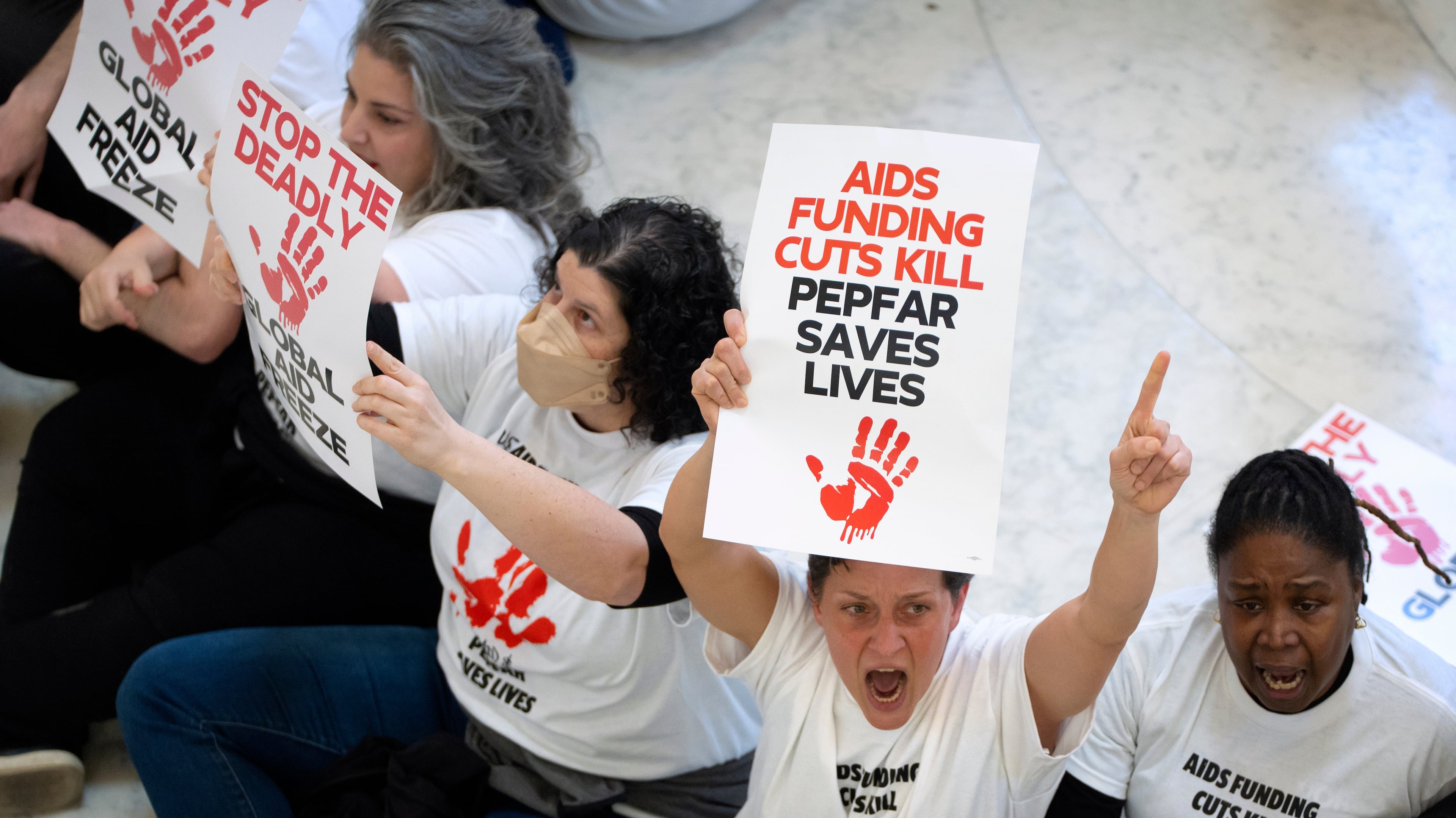 FILE - Demonstrators protest against cuts to American foreign aid spending, including USAID and the PEPFAR program to combat HIV/AIDS, at the Cannon House Office Building on Capitol Hill, Wednesday, Feb. 26, 2025, in Washington. (AP Photo/Mark Schiefelbein, File)