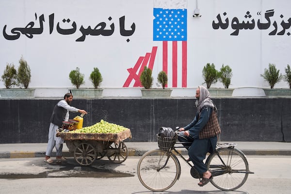 A cyclist passes in front of the former US embassy while a vendor waits for customers, in Kabul, Afghanistan, Thursday, June 5, 2025. (AP Photo/Ebrahim Noroozi)